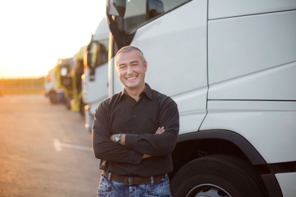 Truck driver in front of his truck. About 45 years old, smiling Caucasian mature adult man.